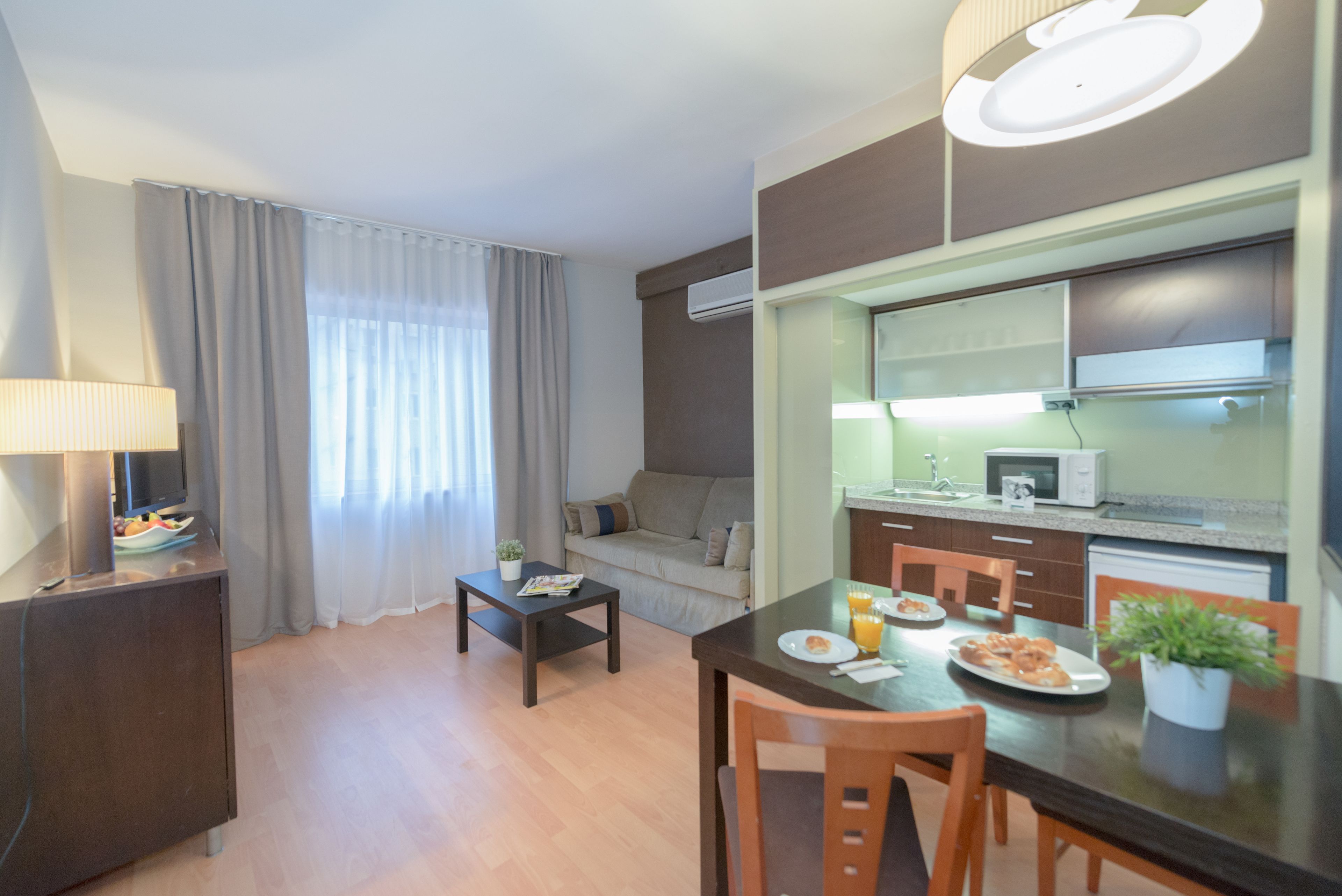 Un espacio habitable compacto con kitchenette, comedor y zona de estar.