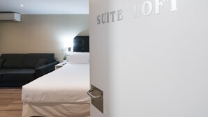 A hotel room with a bed, a sofa, and a wall with the text "SUITE LOFT". - Senator Barcelona Apartments (Barcelona)