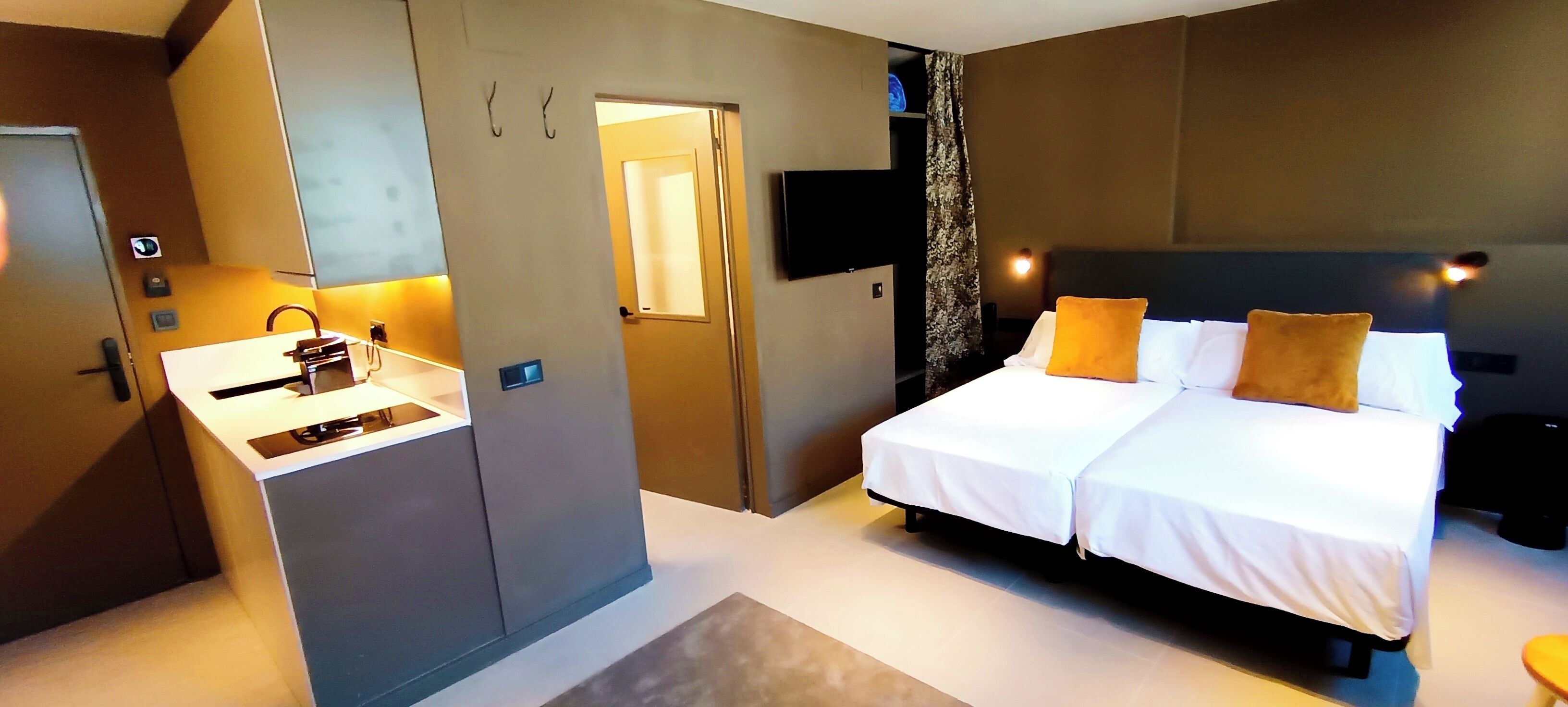 Ein modernes Hotelzimmer mit Bett, Nachttisch und integriertem Kleiderschrank.