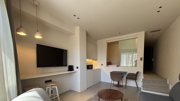 A modern living room with a flat-screen TV, a sofa, a coffee table, and a dining area with chairs. - Senator Barcelona Apartments (Barcelona)