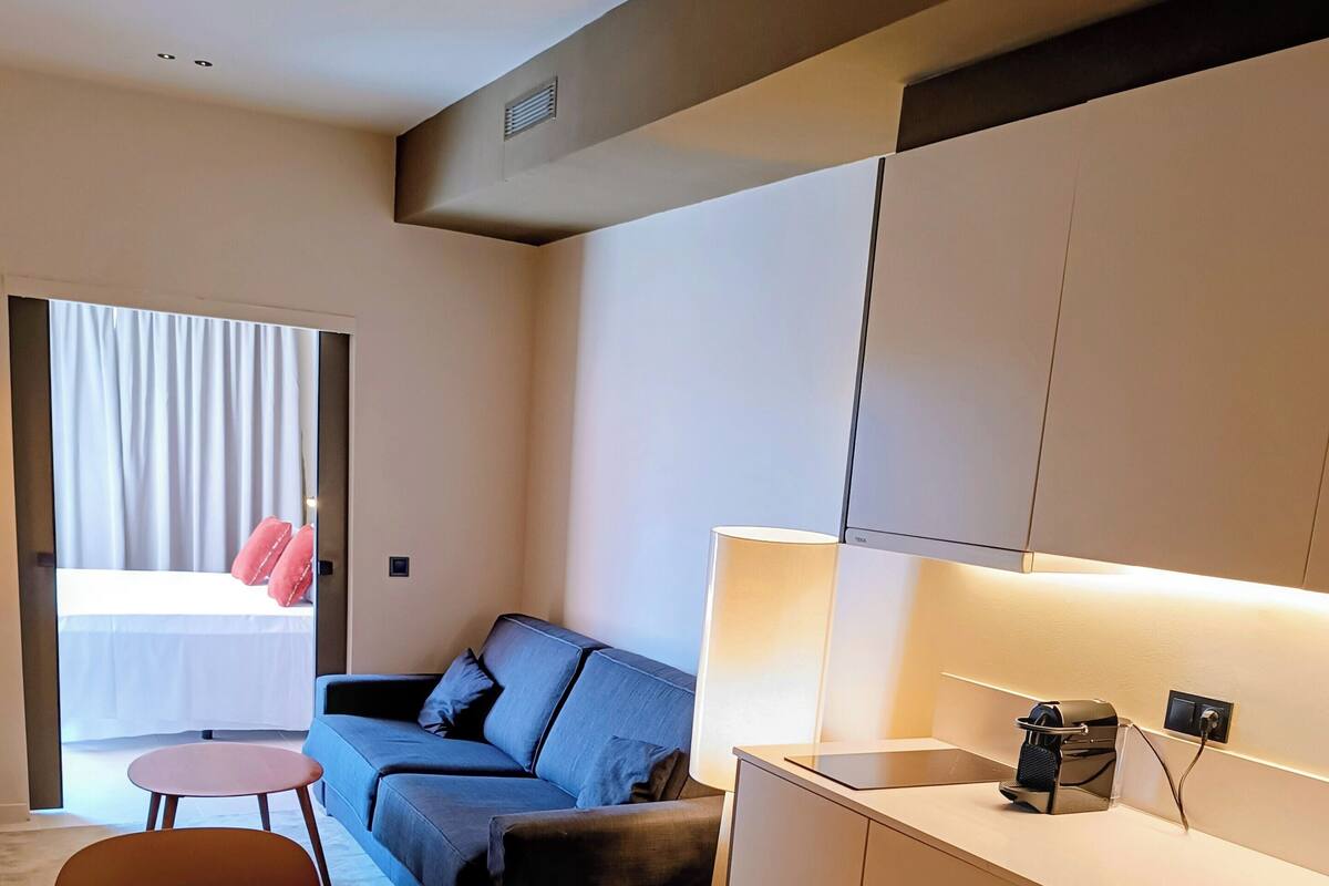 Une chambre d’hôtel moderne équipée d’un canapé, d’une petite table à manger et d’un coin cuisine.