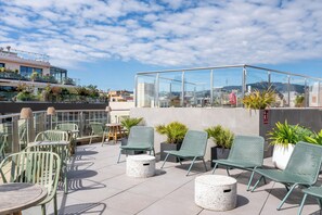 A rooftop terrace with outdoor seating, potted plants, and a glass-enclosed area. - Gran Hotel Havana by Escampa Hotels (Barcelona)