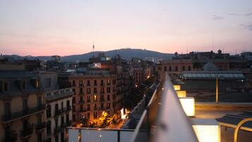 Un paisaje urbano al atardecer con edificios y una colina distante.