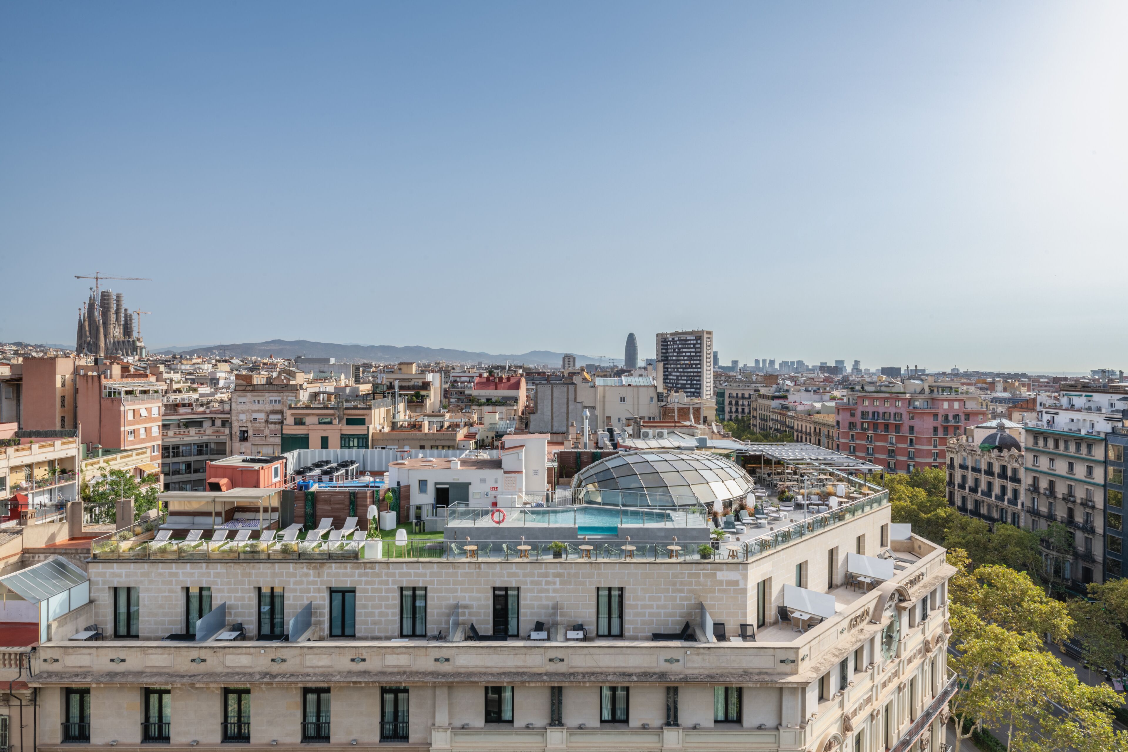 Vista urbana com um edifício imponente, com cúpula e terraço no telhado com mesas ao ar livre.