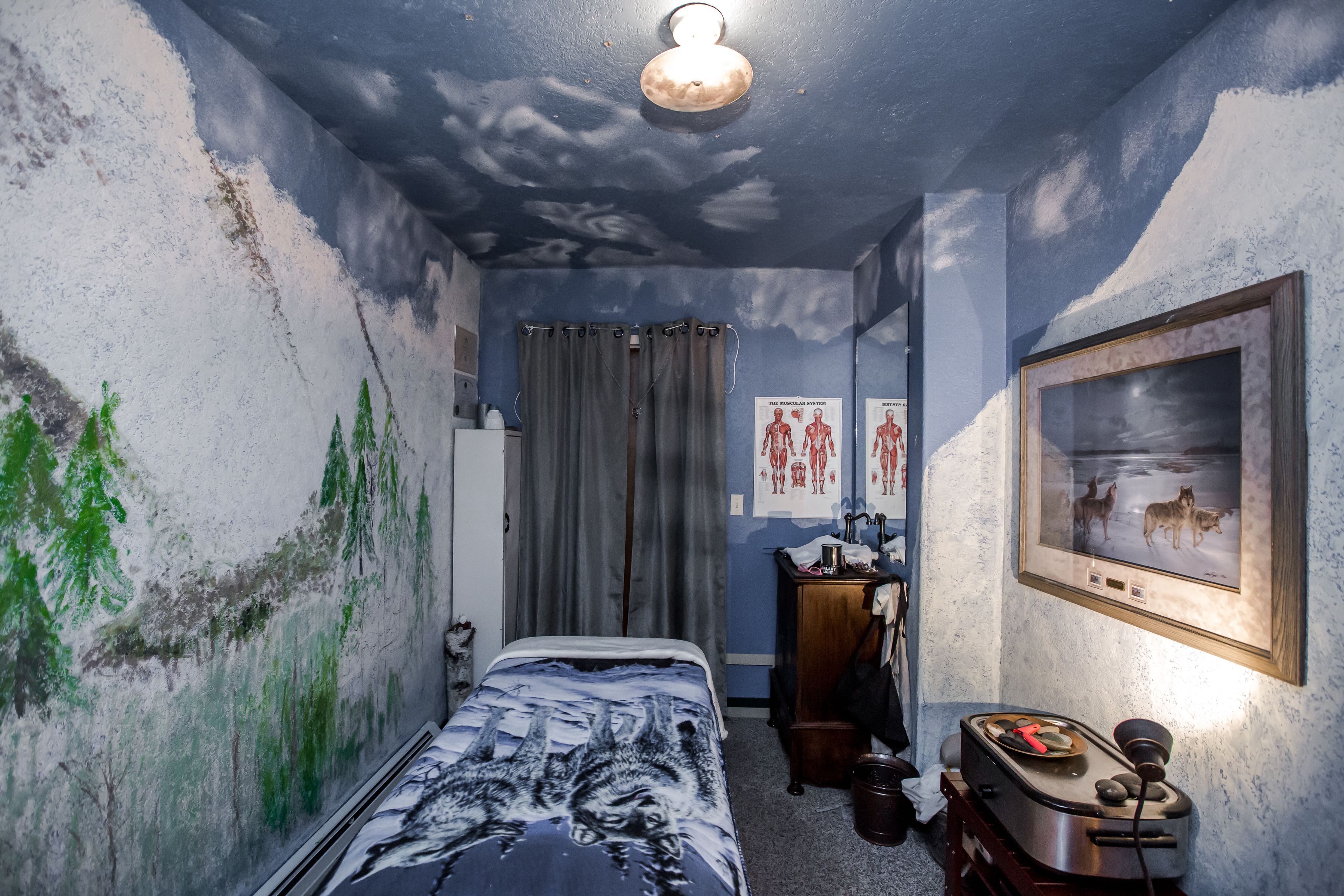 A room with a bed, a desk, a chair, a framed picture on the wall, and a ceiling light.