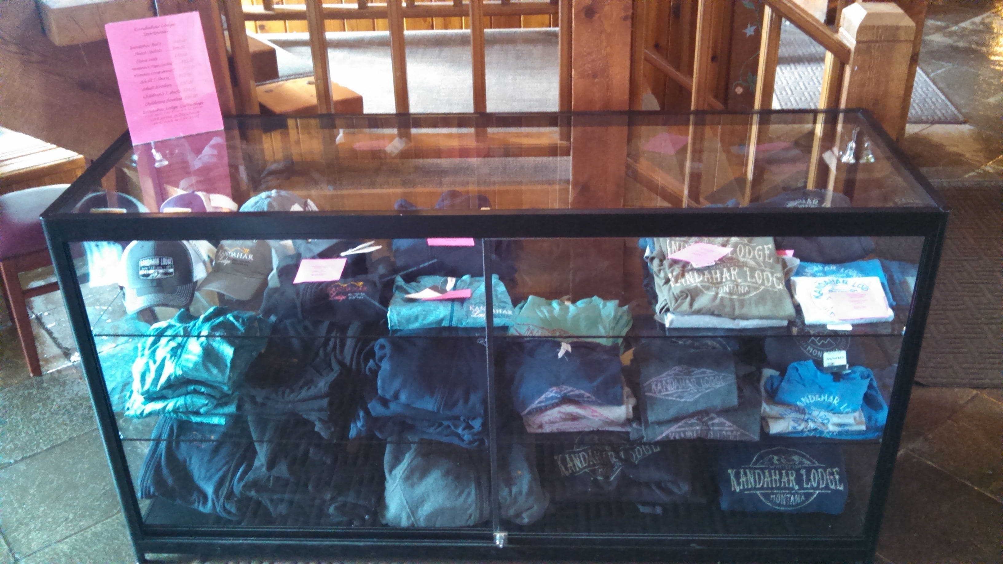 Une vitrine contenant des vêtements pliés, notamment des t-shirts et des pulls à capuche, sur lesquels on peut voir clairement les marques.