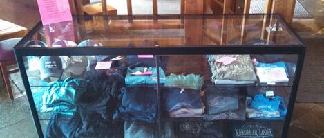 Une vitrine contenant des vêtements pliés, notamment des t-shirts et des pulls à capuche, sur lesquels on peut voir clairement les marques.