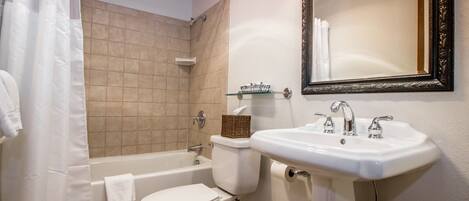 A bathroom with a bathtub, toilet, sink, and a mirror.