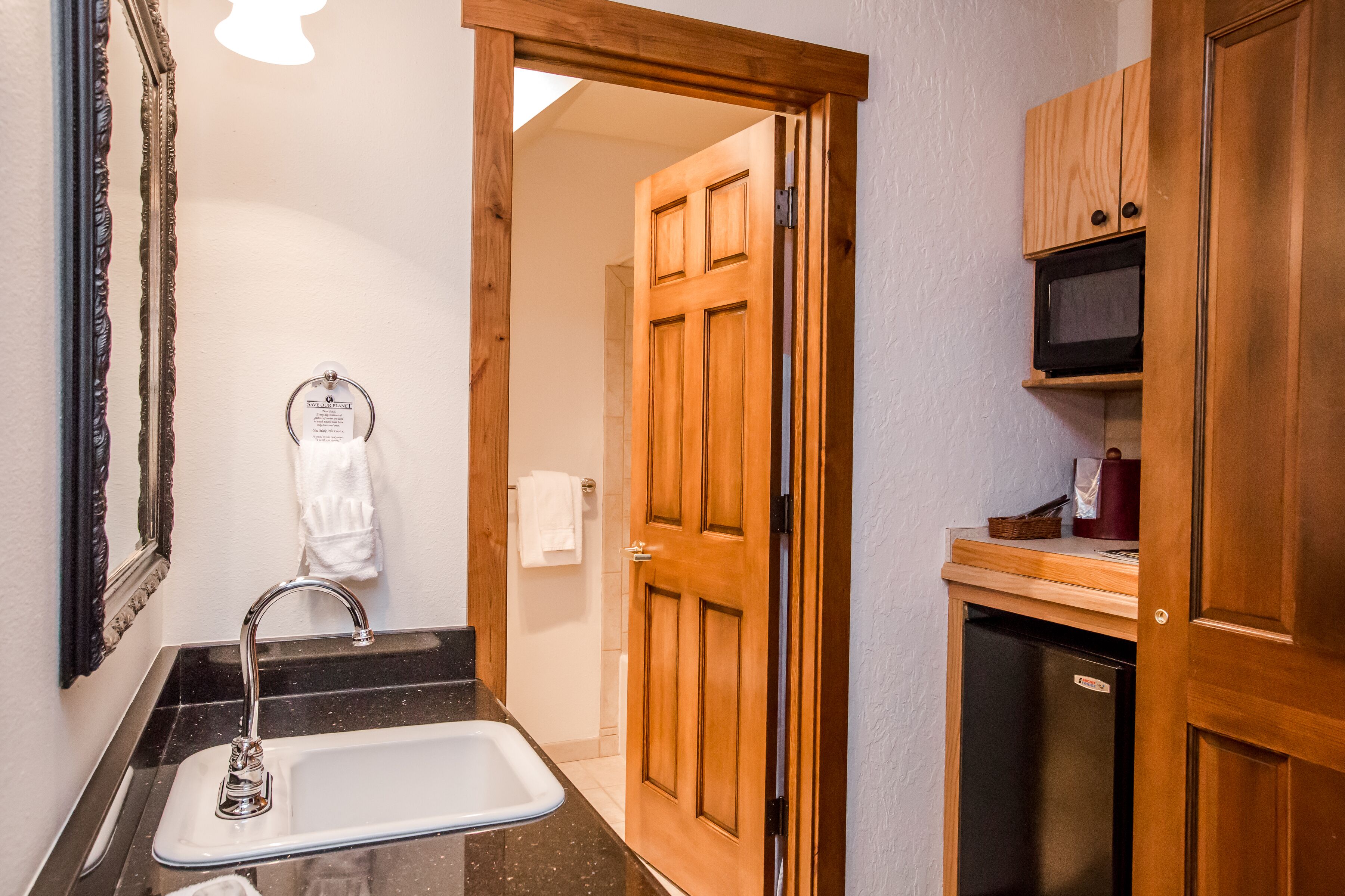 Un baño con lavamanos, espejo y puerta de madera.