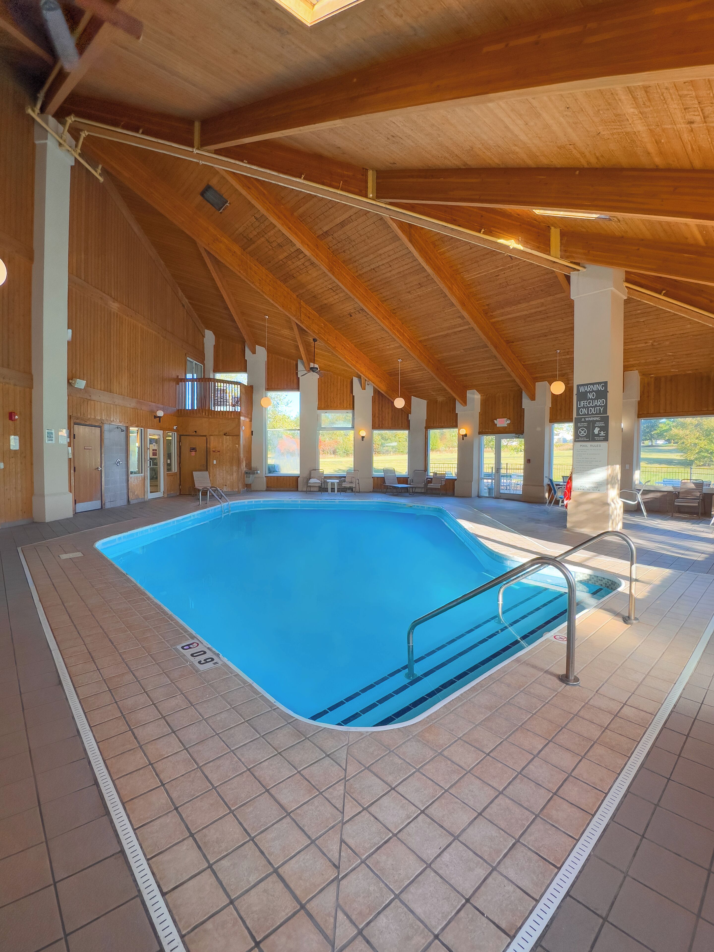 An indoor swimming pool with a tiled floor and a wooden ceiling.