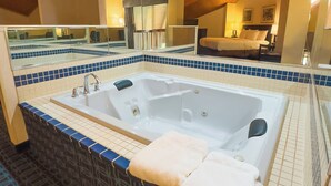A bathroom with a large bathtub, a mirror, and a tiled floor. - Baymont by Wyndham Howell/Brighton (Howell)