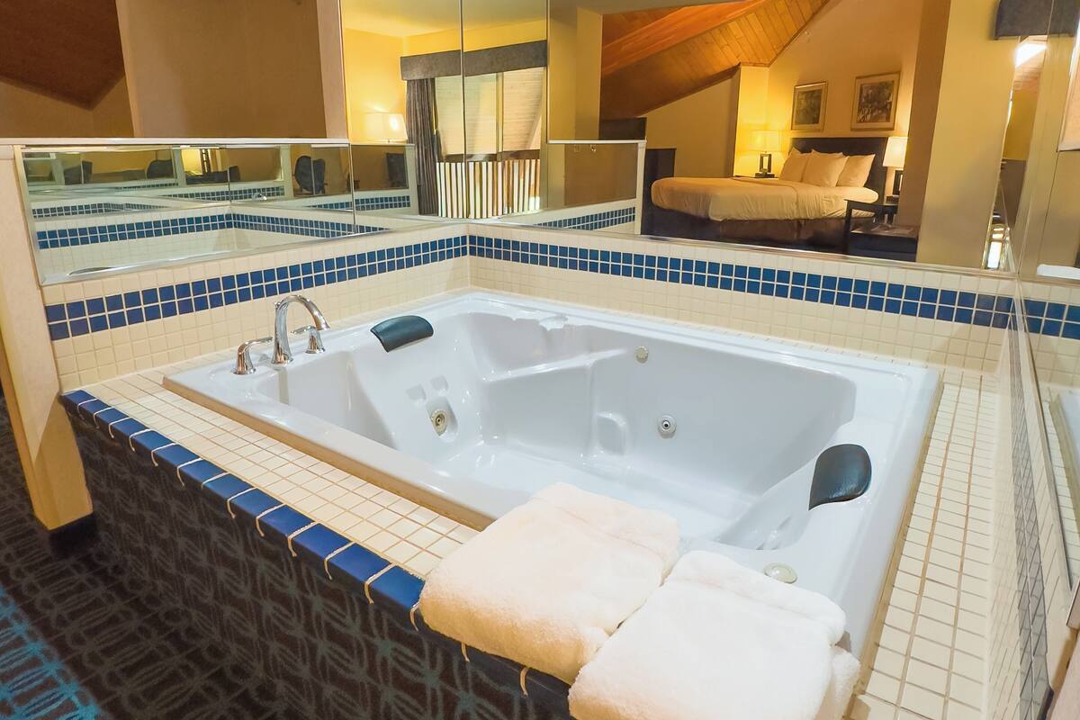 A bathroom with a large bathtub, a mirror, and a tiled floor.