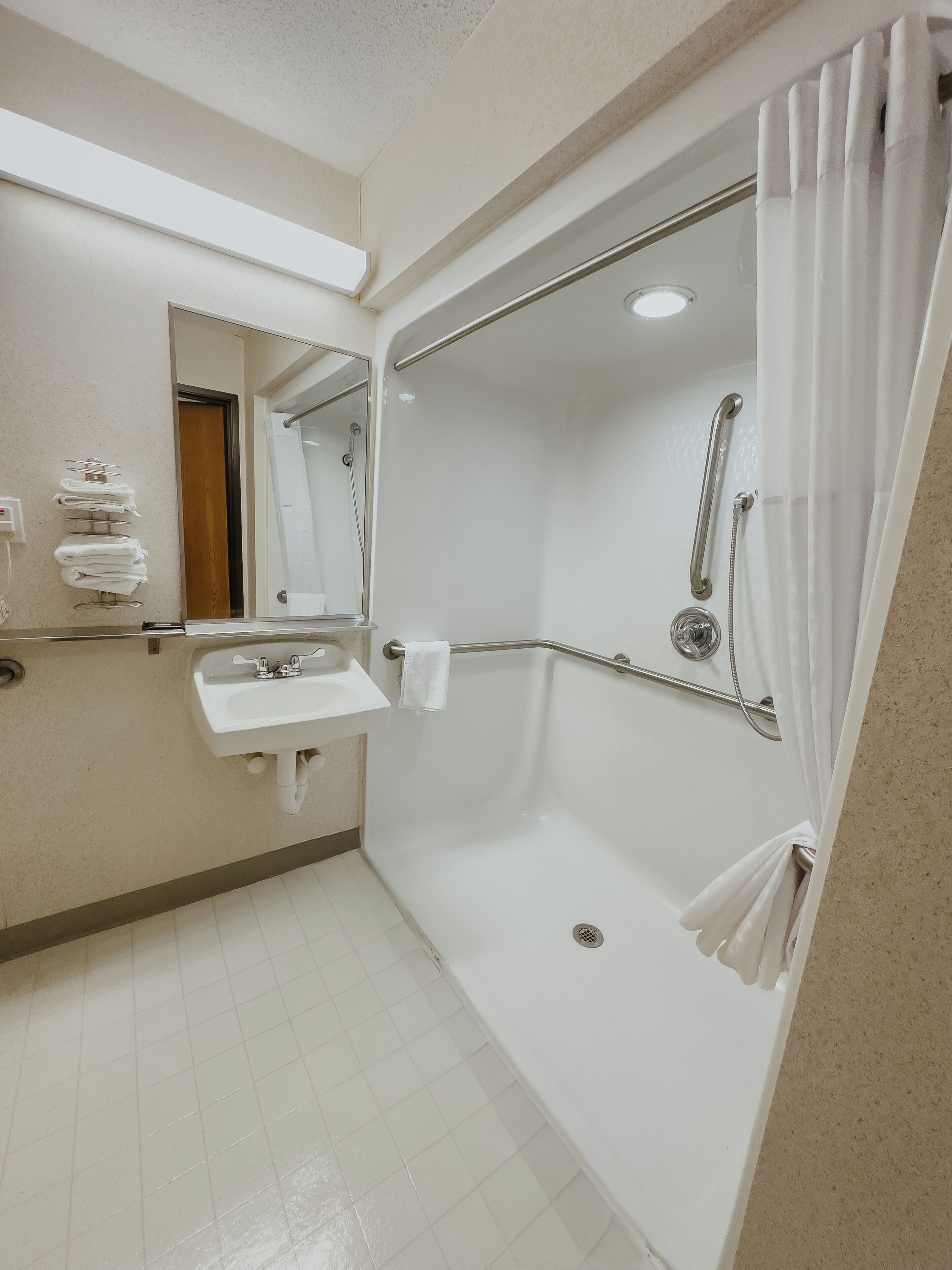 Un baño moderno con cabina de ducha, lavabo y espejo.