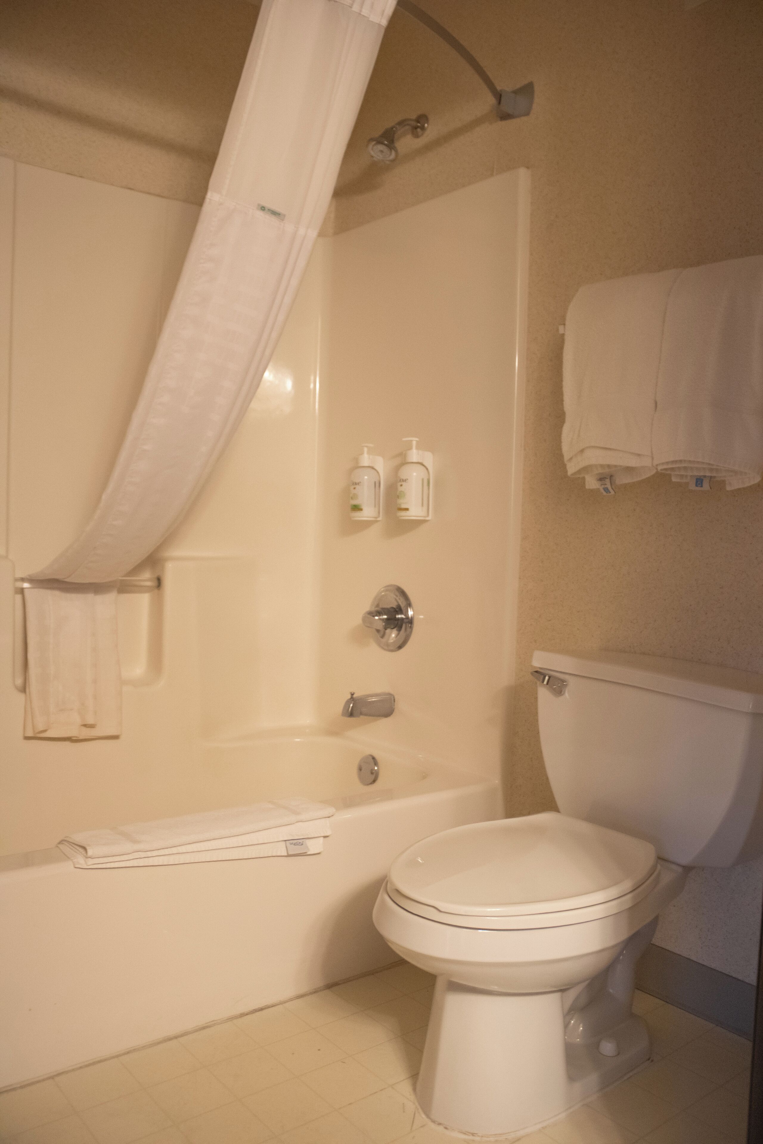 A bathroom with a bathtub, toilet, and shower curtain.
