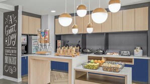 A modern kitchen with wooden cabinets, a breakfast bar, and hanging pendant lights. - Towneplace Suites by Marriott Warren (Warren)