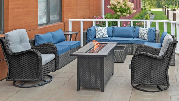 A patio with wicker furniture, a fire feature, and a view of a building and garden. - Towneplace Suites by Marriott Warren (Warren)