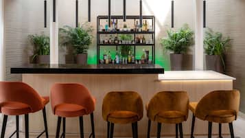 Een bar met een zwarte aanrecht, vier stoelen en een plank met flessen.
