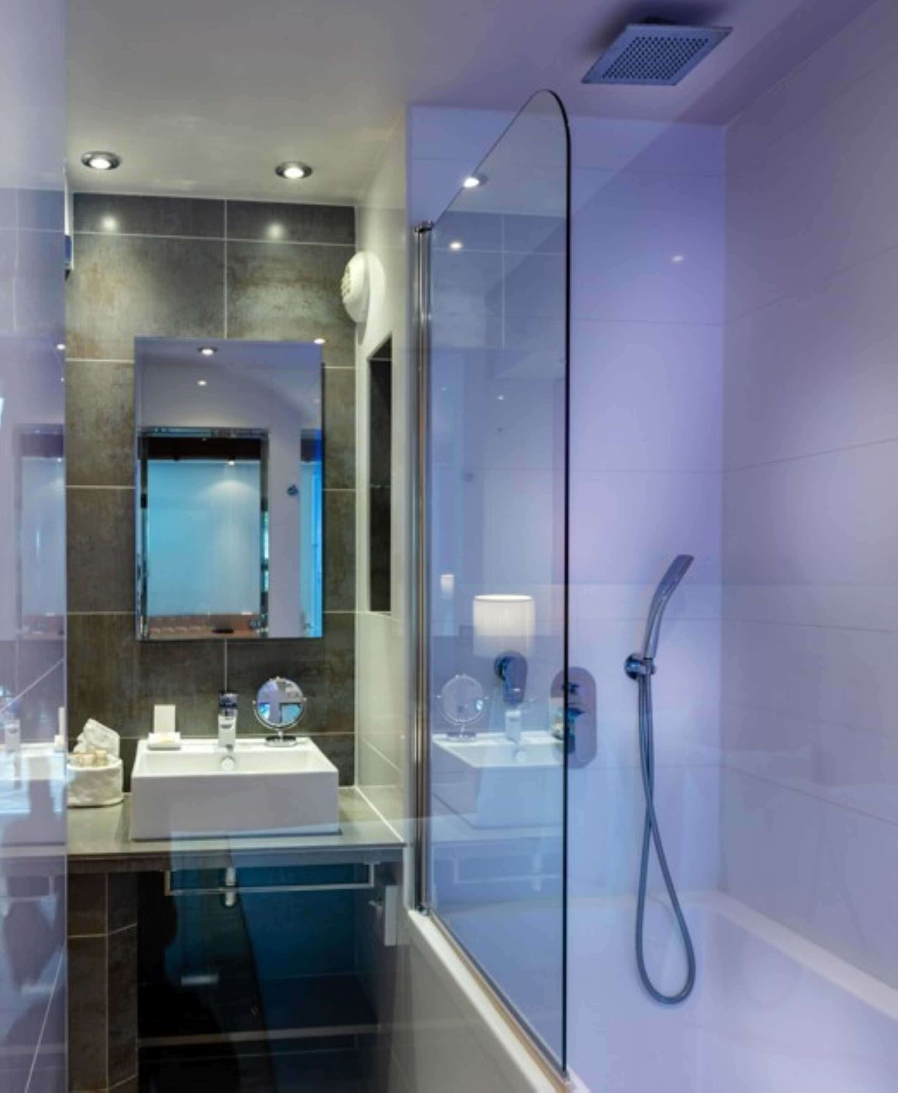 A modern bathroom with a glass-enclosed shower, a vanity with a mirror, and a sink.