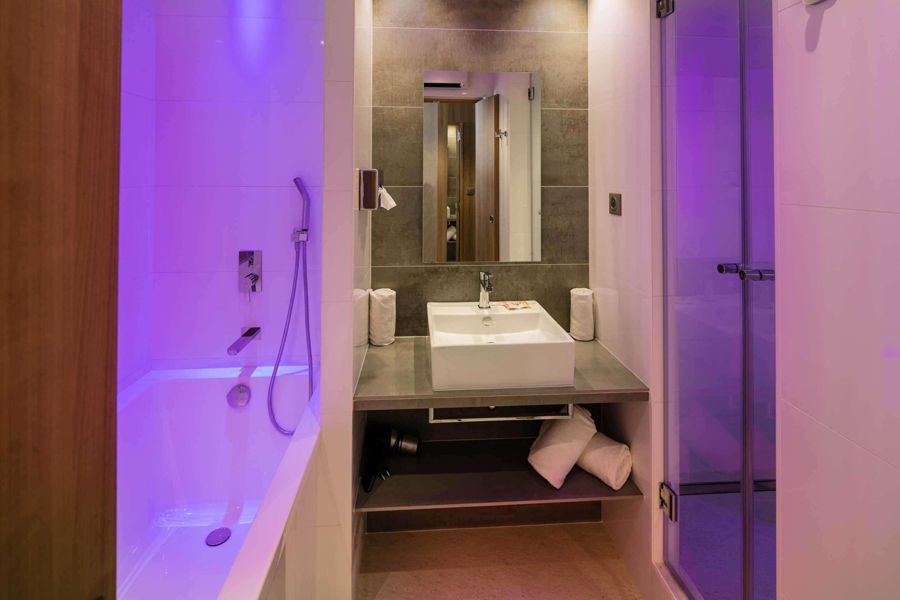 Un baño moderno con cabina de ducha de vidrio, un lavabo blanco y un espejo encima.