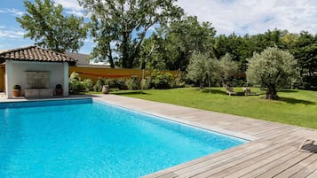 Relax by the serene pool surrounded by lush greenery and mature trees.