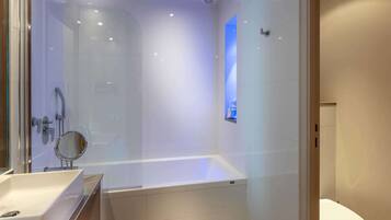 A modern bathroom with a glass-enclosed shower, a standalone bathtub, and a toilet.