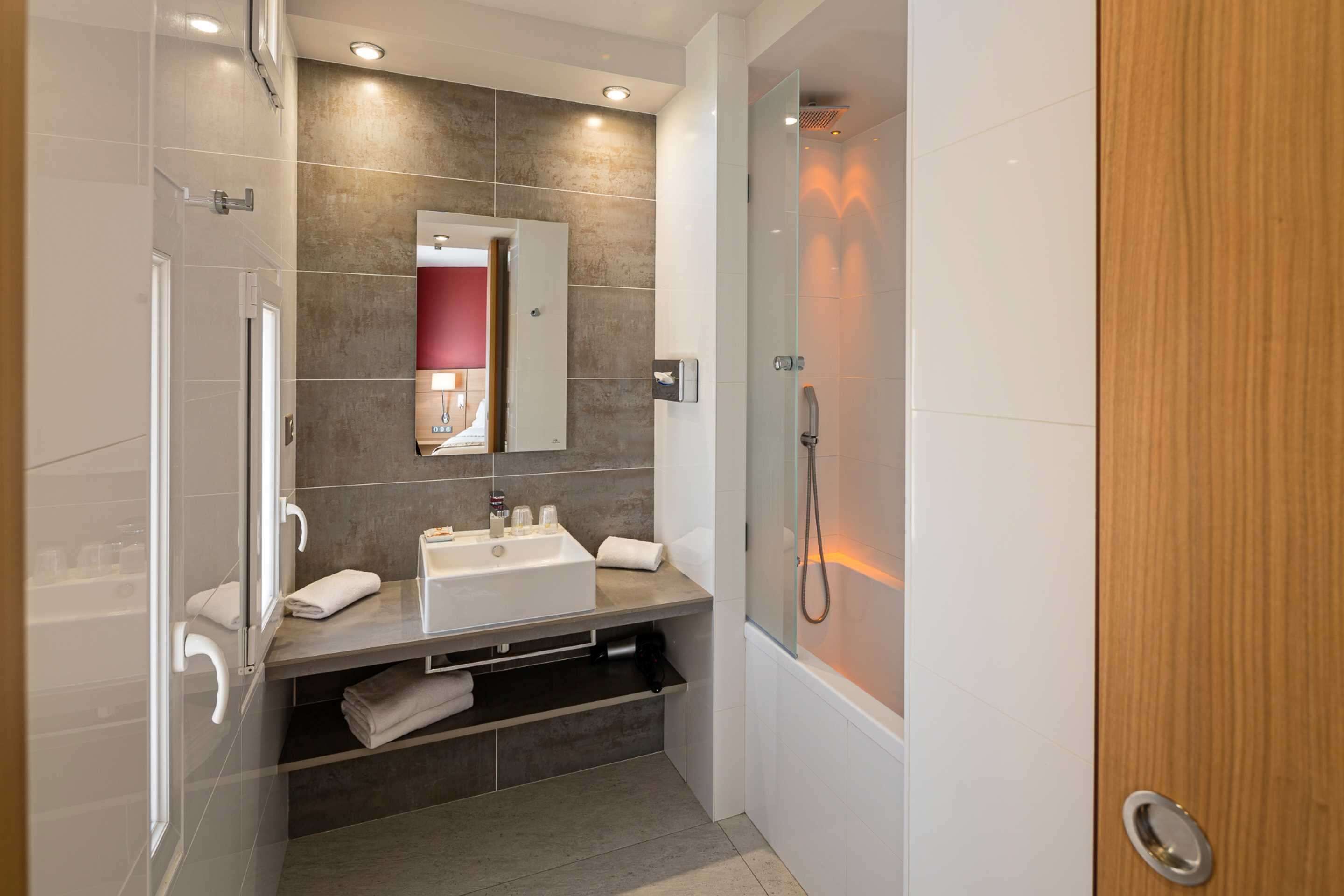 Een moderne badkamer met een douchecabine van glas, een wastafelmeubel met een wastafel en een spiegel.