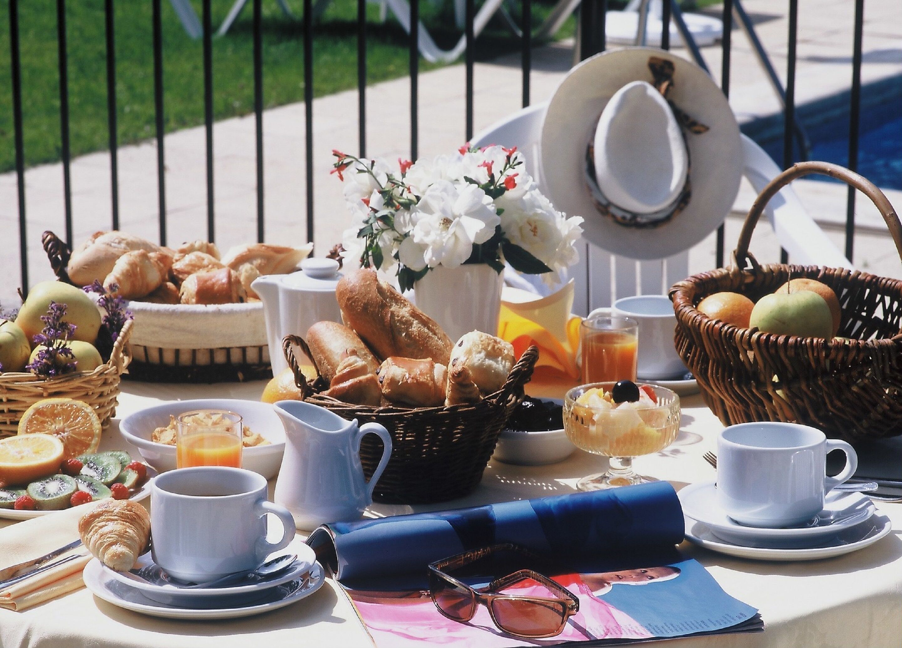 A breakfast table with croissants, fruits, and beverages.