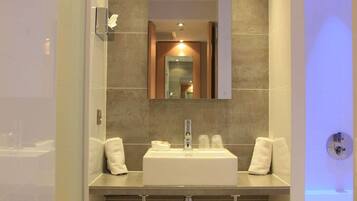 A modern bathroom with a large mirror, a sink, and a shower area.