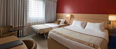Habitación de hotel con dos camas, un escritorio, una silla y una ventana con cortinas.