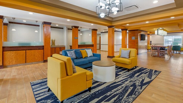 Un hall amplio con un sofá azul, sillones amarillos y una mesa de centro.