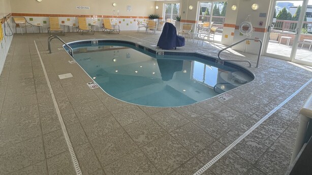 An indoor swimming pool with a tiled floor, a pool ladder, and a 'No Diving' sign on the wall.