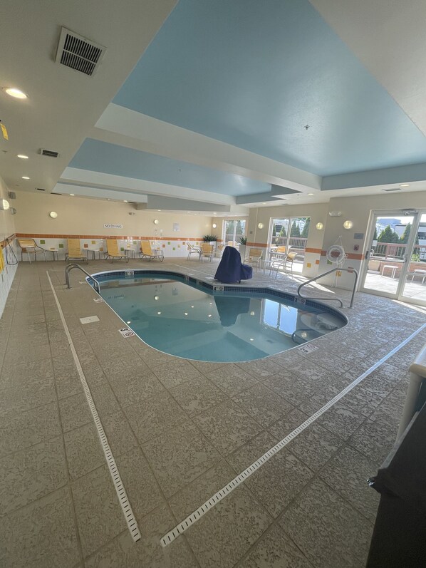 An indoor swimming pool with a tiled floor, a pool ladder, and a 'No Diving' sign on the wall.