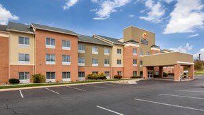 A hotel with a brick facade, multiple windows, and a parking lot.