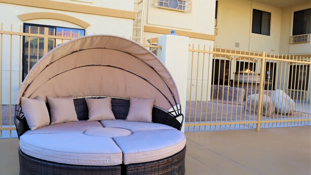 A round outdoor seating area with a canopy, cushioned seating, and a wicker base. - Oasis Inn & Suites Joshua Tree - 29 Palms (Twentynine Palms)