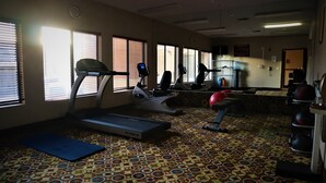 A gym with treadmills, elliptical machines, and a red exercise ball. - Oasis Inn & Suites Joshua Tree - 29 Palms (Twentynine Palms)