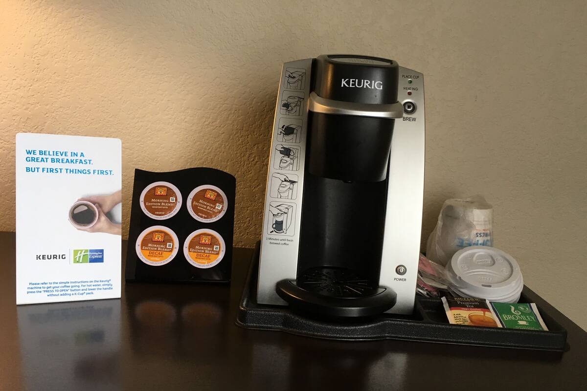 A Keurig coffee maker with four coffee pods, a power button, and a water reservoir on a table.