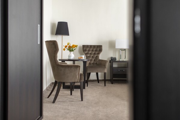 Habitación de hotel con comedor que incluye dos sillas, una mesa y un florero con flores.