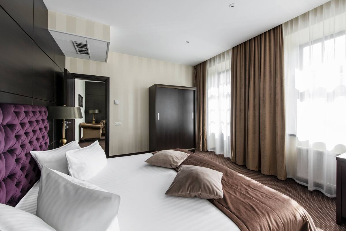 Una camera d'albergo con un letto grande, un armadio, un angolo salotto e vista sull'esterno.