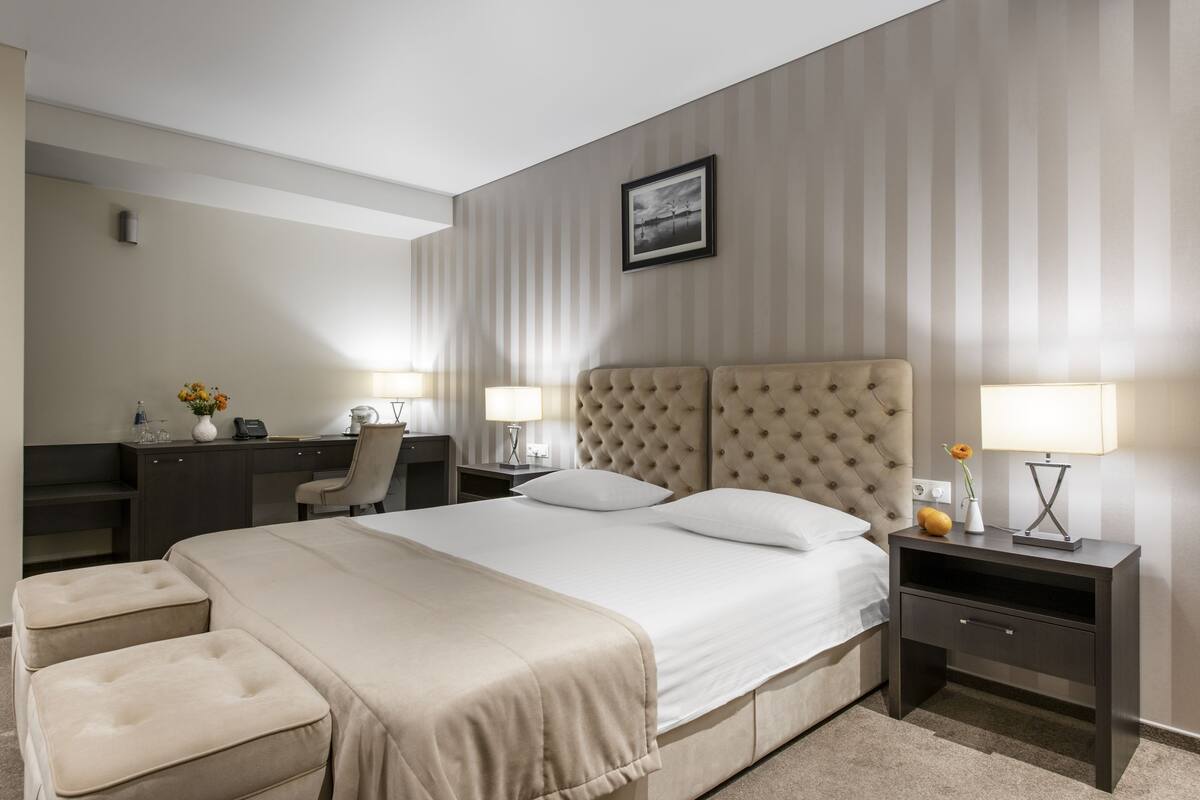 Una camera d'albergo con un letto grande, due comodini, una scrivania e una sedia.