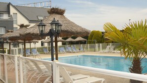 A swimming pool with lounge chairs and thatched umbrellas.