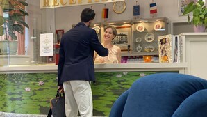 A reception area with a 'RECEPTION' sign, a clock, flags, and a counter with various items. - Garten - & Kunsthotels Gabriel (Vienna)