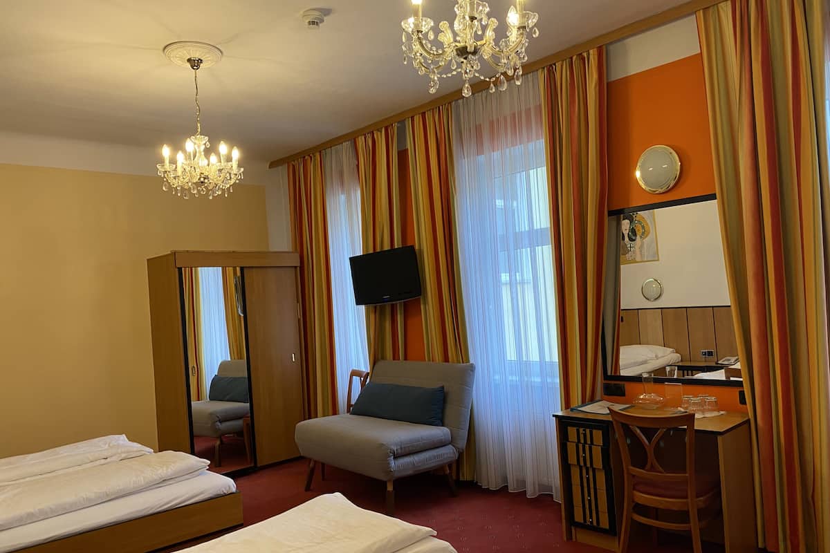 A hotel room with two beds, a desk, a chair, a television, and a mirror.