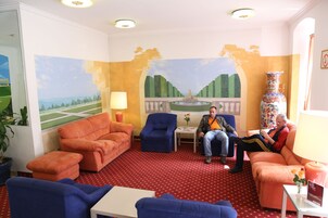 Um quarto com sofás laranja e azuis, uma mesinha com abajur e um vaso decorativo.
