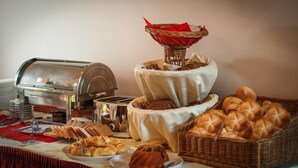 A buffet setup with a toaster, bread, pastries, and a basket of rolls. - Garten - & Kunsthotels Gabriel (Vienna)
