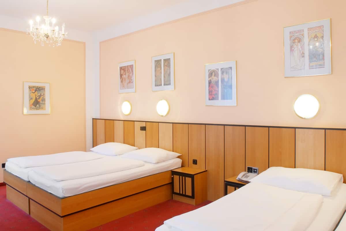 A hotel room with two single beds, a wooden headboard, a chandelier, and wall-mounted light fixtures.
