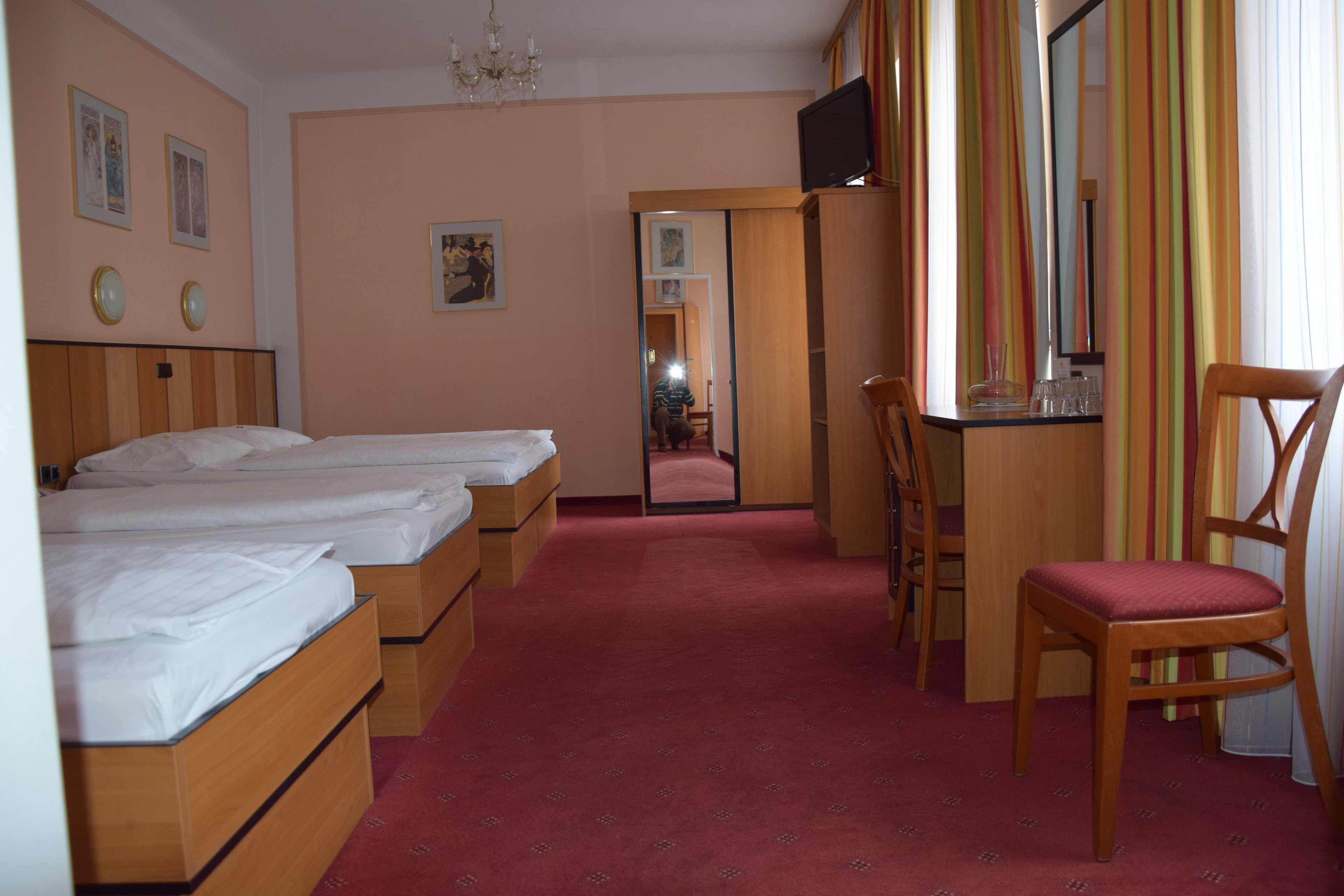 A hotel room with two beds, a desk with a chair, a TV, and a mirror.