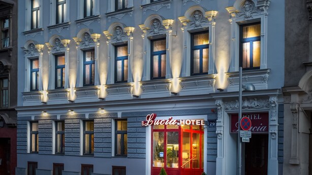 Un bâtiment historique à la façade classique, doté de nombreuses fenêtres et d’une entrée au rez-de-chaussée portant l’inscription « HÔTEL El Lucia ».