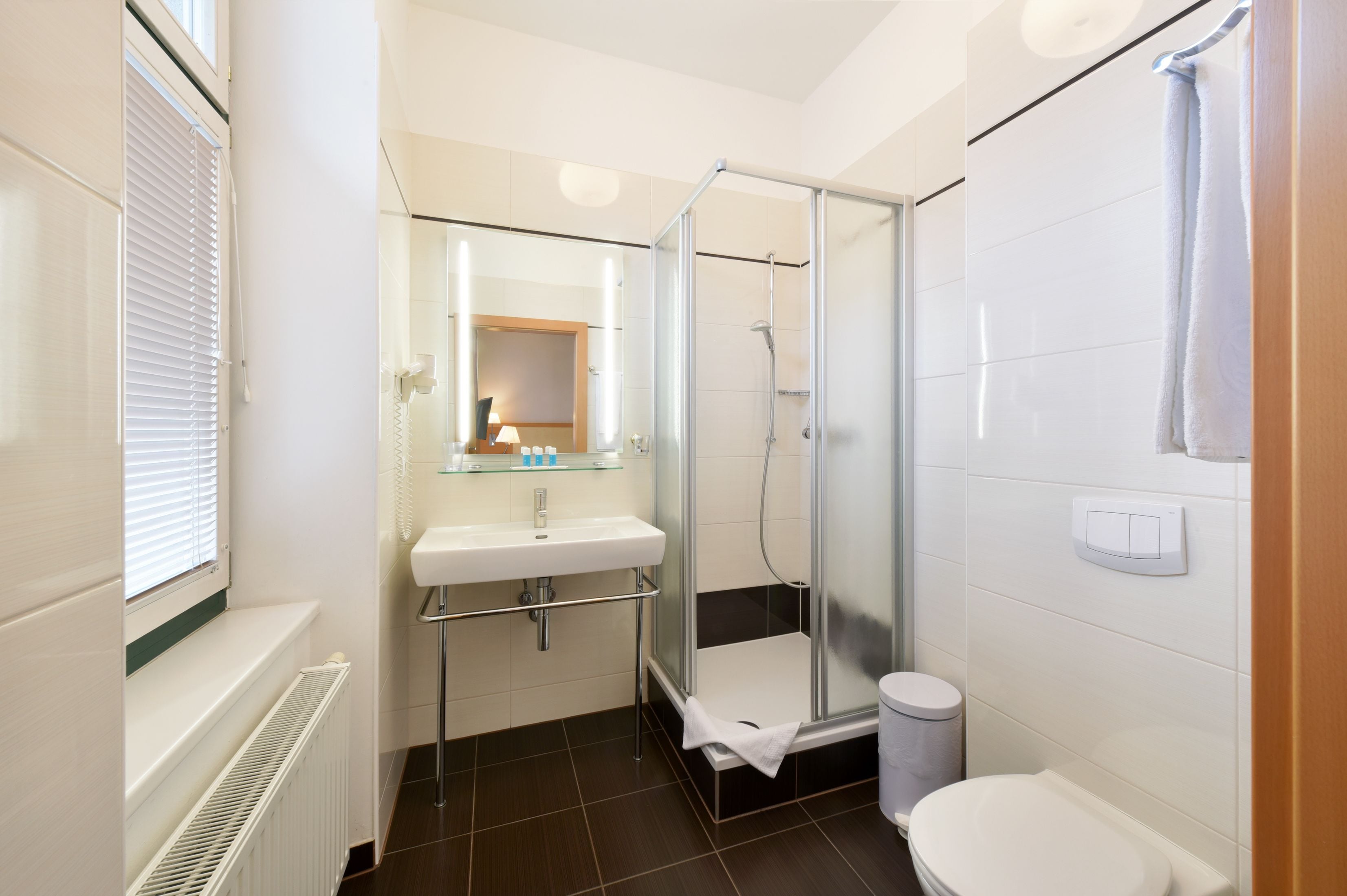 A bathroom with a glass-enclosed shower, a white sink, and a toilet.