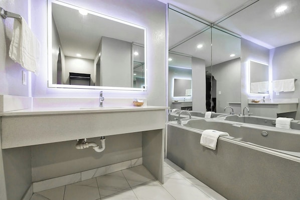 A modern bathroom with a large mirror, two sinks, and a bathtub. - Downtowner Inns Houston (Houston)