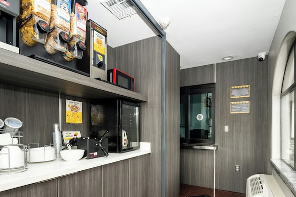 A kitchen area with a microwave, waffle maker, and waffle display. - Downtowner Inns Houston (Houston)